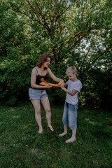 Fototapeta premium A mother and her son with hearing aids launch a paper airplane in a park, a heartwarming moment of inclusive play and bonding in nature. Perfect for disability awareness and family lifestyle content