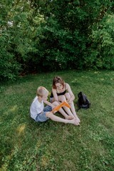 Fototapeta premium A mother and her son with hearing aids launch a paper airplane in a park, a heartwarming moment of inclusive play and bonding in nature. Perfect for disability awareness and family lifestyle content