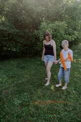 Fototapeta premium A mother and her son with hearing aids launch a paper airplane in a park, a heartwarming moment of inclusive play and bonding in nature. Perfect for disability awareness and family lifestyle content