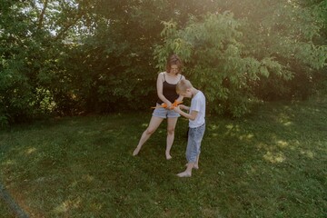 Fototapeta premium A mother and her son with hearing aids launch a paper airplane in a park, a heartwarming moment of inclusive play and bonding in nature. Perfect for disability awareness and family lifestyle content