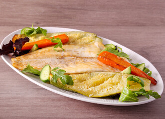 Baked white fish fillet with vegetables on plate