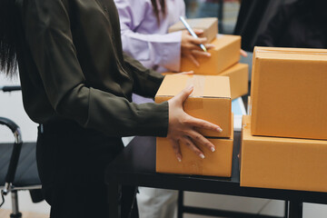 Portrait of Starting small businesses SME owners, two Asian woman check online orders Selling products working with boxs freelance work at home office, sme business online small medium enterprise