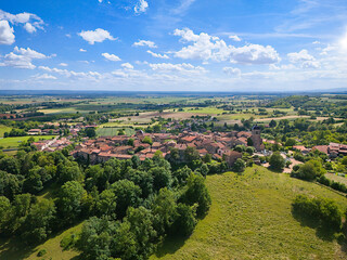Aerial view of the medieval hilltop town of Pérouges in the Ain region, France. Red-roofed stone buildings and fortifications amid lush countryside. Concept: heritage, tourism.