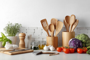 Well-organized kitchen countertop with cooking utensils, fresh vegetables, garlic, herbs, and wooden tools, healthy food concept