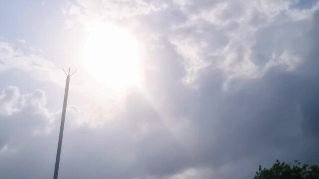 Bright rays of sun piercing through clouds, reaching the copper lightning rod antenna earthed to the ground and connected with Solar Panels, convert sunlight into electricity on the farm.