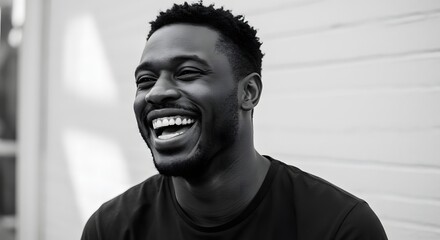 A monochrome portrait of a smiling man with short hair wearing a dark shirt against a light background