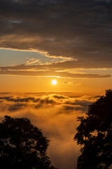 golden sunset over the clouds or fog of tuscany in a view from Montepulciano into the backlight of the going sun with silhouettes of trees