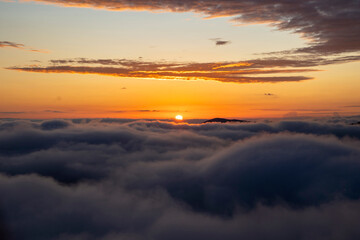 golden sunset over the clouds or fog of tuscany in a view from Montepulciano into the backlight of the going sun