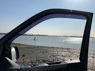 View of sail boat on river through car window