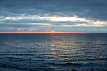 The ocean is calm and the sun is setting