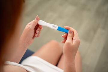 A woman holds a pregnancy test with two stripes in her hands