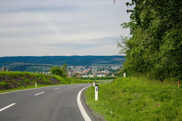Countryside road leading to distant village and hills
