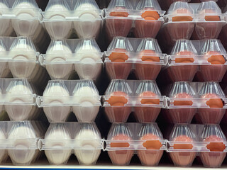 White and brown eggs packaged in clear plastic containers filling supermarket shelf