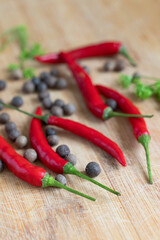 five bright red chili peppers and peppercorns on a neutral background