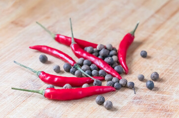 bright hot red chili peppers on a wooden surface surrounded by aromatic peppercorns