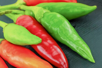 hot green and red chili peppers lie on a black background, small