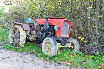 an old red farm tractor against the background of the forest