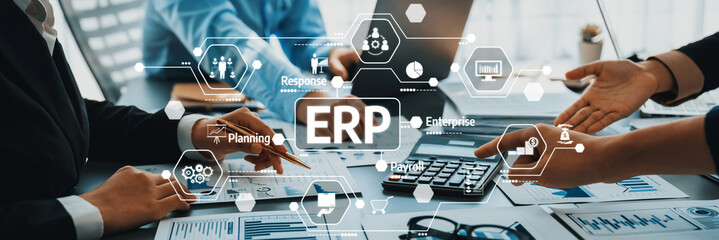Business meeting with hands on documents, laptop, and ERP graphic overlays discussing enterprise resource planning and project management strategies. Amity