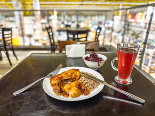 Contemporary urban cafeteria lunch featuring baked chicken over buckwheat with beetroot salad and ruby red fruit drink