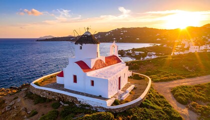 Aerial view of a whitewashed church and windmill at sunset