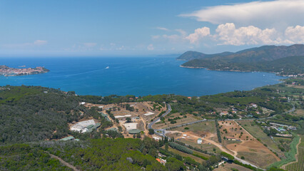 Aerial view of a coastal bay with blue sea, hills, and rural landscape