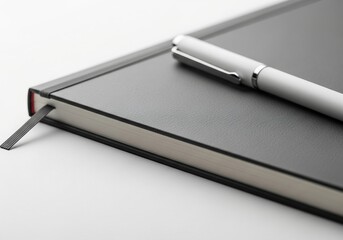 Elegant white pen resting on a textured black notebook with ribbon marker