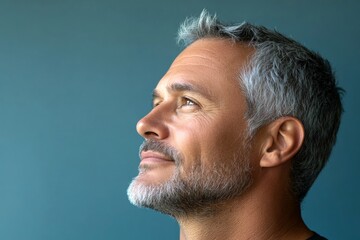 Obraz premium Creative of style for aging men. Blue solid background. A classic and stylish male with a natural smile. Modish men's crew cut haircut - midlife white man with grey hair.