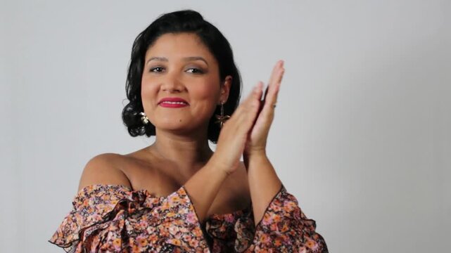 Cheerful brown skin woman clapping hands with elegance. Attractive brunette female model in horizontal video with copy space on gray background.