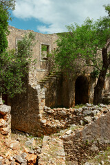 Ancient two-story stone building ruins with arched openings and stone staircase in Mediterranean archaeological site
