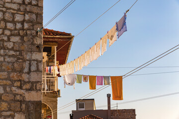 Colorful laundry hanging between stone houses in Ulcinj Old Town under clear sky, Montenegro