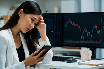 Stressful young beautiful Asian businesswoman focusing on smartphone, analyzing possible risk to...