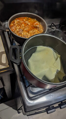 Lasagna pasta sheet, boiling water, and heating red pozole. Preparing lasagna for Christmas dinner.