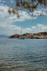 Traditional Greek coastal village with boats anchored in turquoise Mediterranean waters.