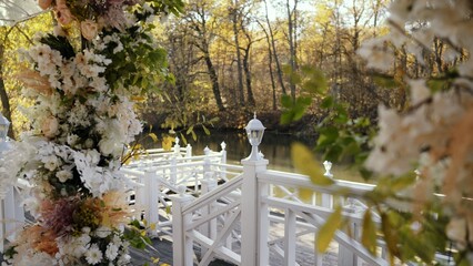 Beautiful floral arrangement adorns a wedding location by a tranquil lake, creating a picturesque...