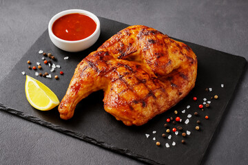 Grilled half chicken on black slate plate photo 