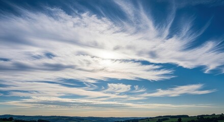 Obraz premium Cirrus clouds streaking across bright blue sky, faint horizon