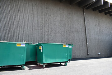 Green dumpsters behind large event center.