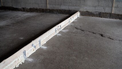 Construction workers are using wooden guides and polyurethane expanding foam to prepare the area for concrete pouring
