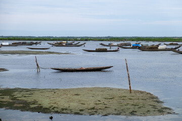 Fototapeta premium Colorful traditional Vietnamese fishing boats anchored near a beach with large coastal rocks in the background.