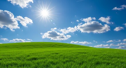 Obraz premium Idyllic summer landscape featuring a rolling green hill under a radiant sun, fluffy clouds, and a vast blue sky.