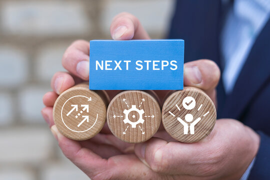 Business person holding blocks with icons sees the inscription: NEXT STEPS. Next Steps Business Progress Development Career Concept.