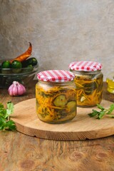 Pickled vegetable salad of cucumbers and carrots in glass jars on a wooden background. Canning, preparations. Step-by-step recipes.