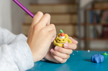 A young girl playing with colorful modeling dough and pencils on a blue table. 