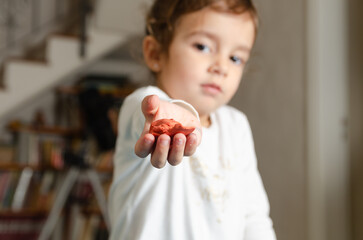 A cute little girl showing a piece of modeling dough.