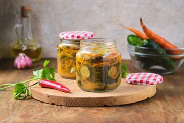 Pickled vegetable salad of cucumbers and carrots in glass jars on a wooden background. Canning, preparations. Step-by-step recipes.