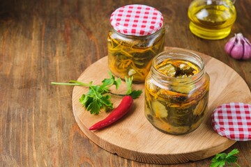 Pickled vegetable salad of cucumbers and carrots in glass jars on a wooden background. Canning, preparations. Step-by-step recipes.