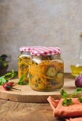 Pickled vegetable salad of cucumbers and carrots in glass jars on a wooden background. Canning, preparations. Step-by-step recipes.
