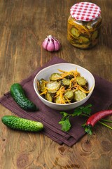 Pickled vegetable salad of cucumbers and carrots in a ceramic bowl on a wooden background. Canning, preparations. Step-by-step recipes.