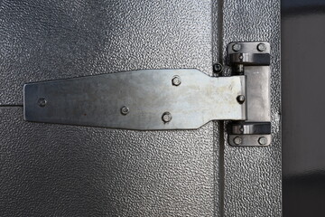 Large external hinge on industrial freezer door.