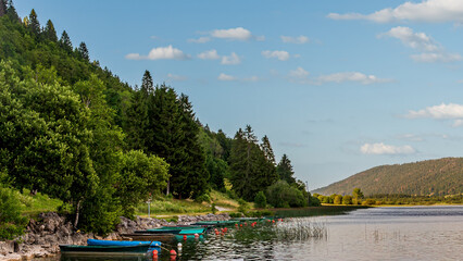 Rowboats in Lac des Rousses, forest and mountain in Summer. Les Rousses, Jura, France.